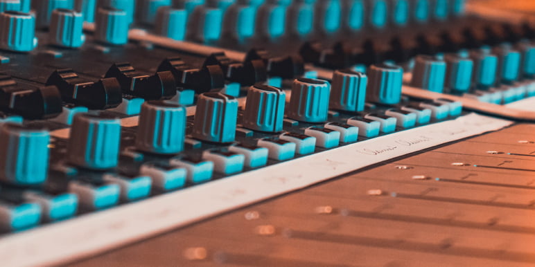 Blue EQ buttons on an audio music mixer console recording the sound from the latest Momentum Investments video shoot.
