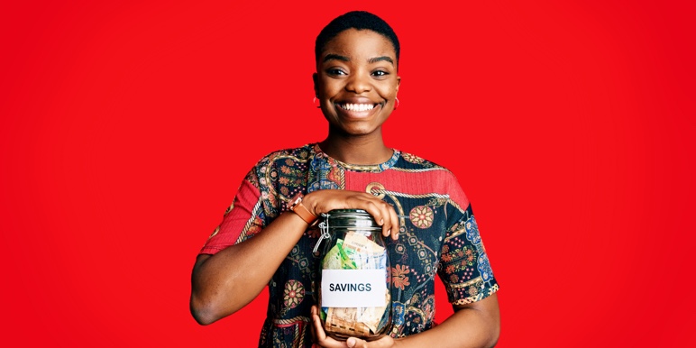 Young black woman holding savings jar with coins.
