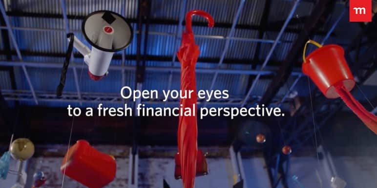A red umbrella and loudspeaker are hanging from a factory ceiling.