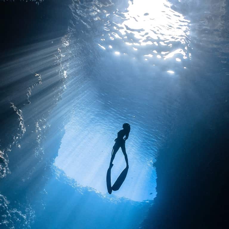 A deep-sea diver keeps her momentum going and swims to the ocean's surface.
