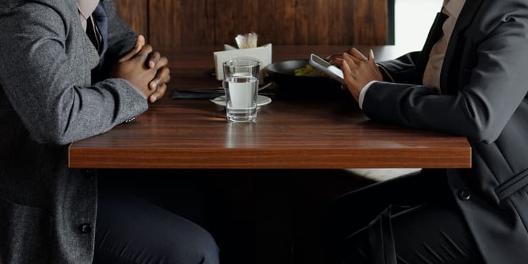 A financial adviser seated at a table discussing the drafting of a Will.