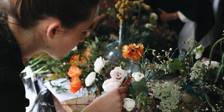 A young lady at a funeral placing a white rose onto a coffin.