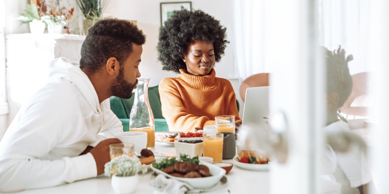 A mother and a father having breakfast with their child at a kitchen table.