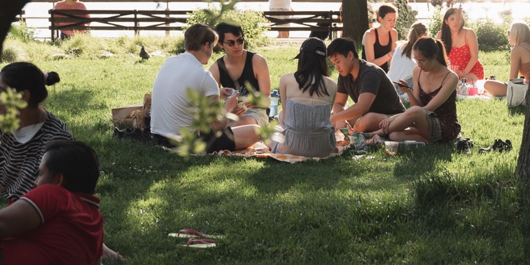  Little groups of people sitting on the grass with their picnics enjoying the sunshine and warm air as they have been vaccinated against COVID-19.