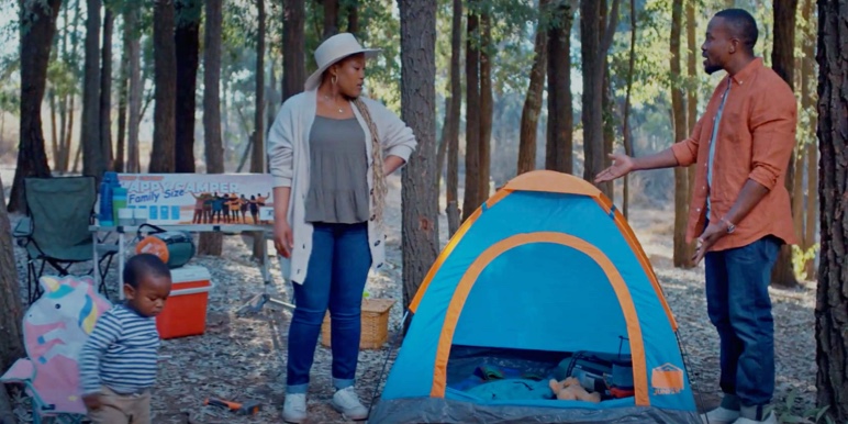 Husband takes his family on a camping trip in the woods but has bought a very small tent to fit a family of 4. The wife is frustrated and annoyed as they try to squeeze themselves into a small tent to take shelter as it’s about to rain.