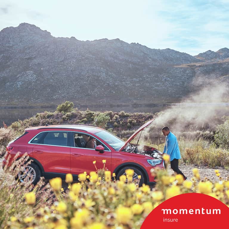 Cheslin Kolbe looking under the hood of his car as the steam escapes while his partner is in the passenger seat using the Safety Alert feature from Momentum Insure available on the Momentum App.