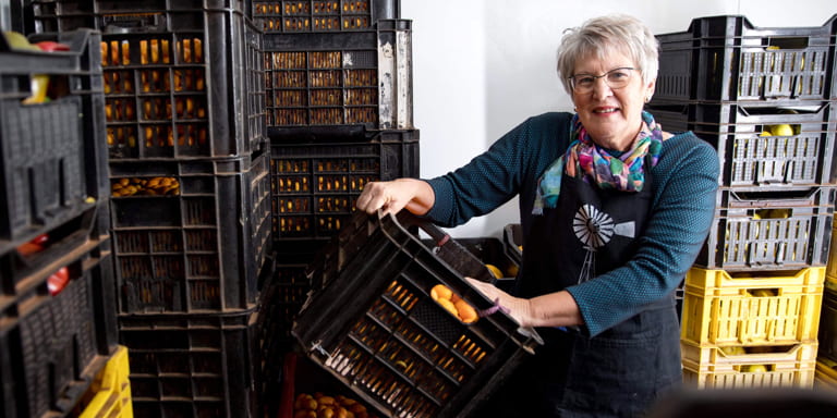 #NoApologyForMySuccess Ina Lessing, entrepreneur and business woman, standing holding a crate filled with fresh fruit ready to be made into delicious jams.