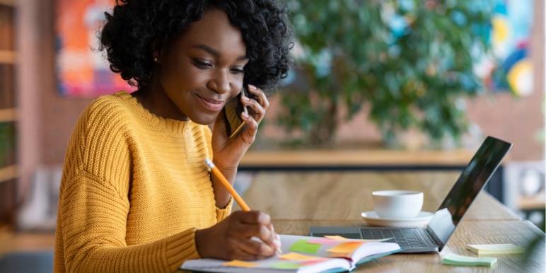 A young lady writing down her financial goals in her journal