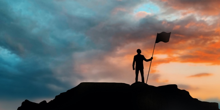 A person on top of a mountain with a flag