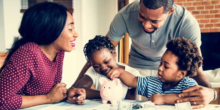 A Black family with young children putting money in a piggy bank