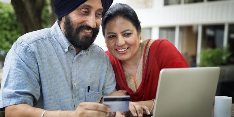 An Indian couple sitting at their laptop with their credit card