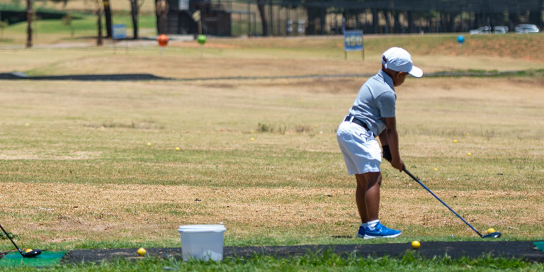 Ngobani dressed in white shorts, light grey golf t-shirt and a white cap aiming to drive at the driving range.