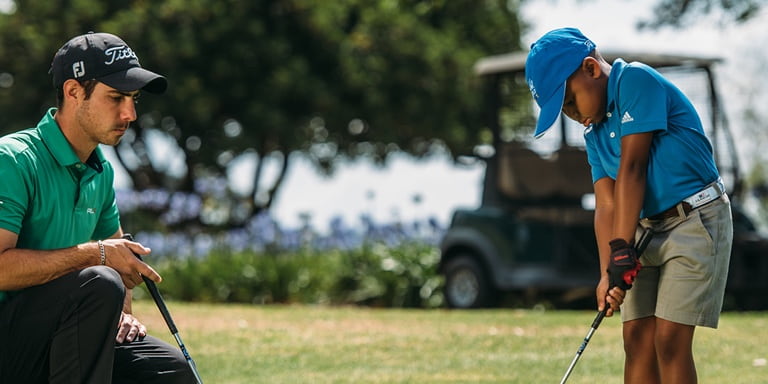 Ngobani with his coach Byron Nel practising golf on the greens of a golf course.