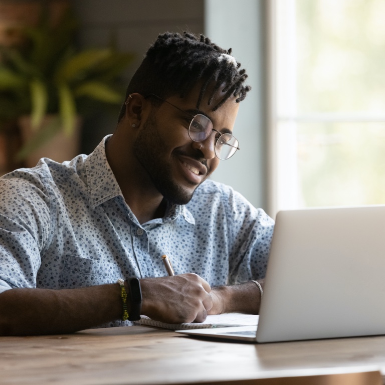 A young man is seated at a desk. He’s busy completing his online Will process on his laptop.