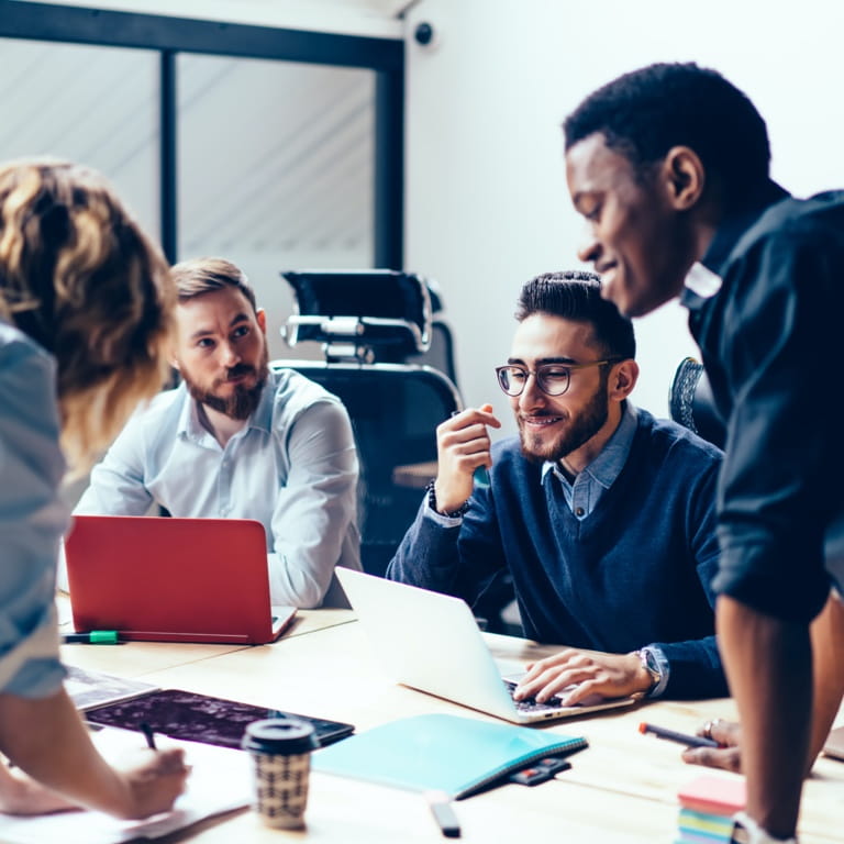 Four colleagues sit around a table discussing ideas for a project.