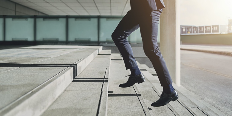 A man in a suit running up the stairs to his office block.