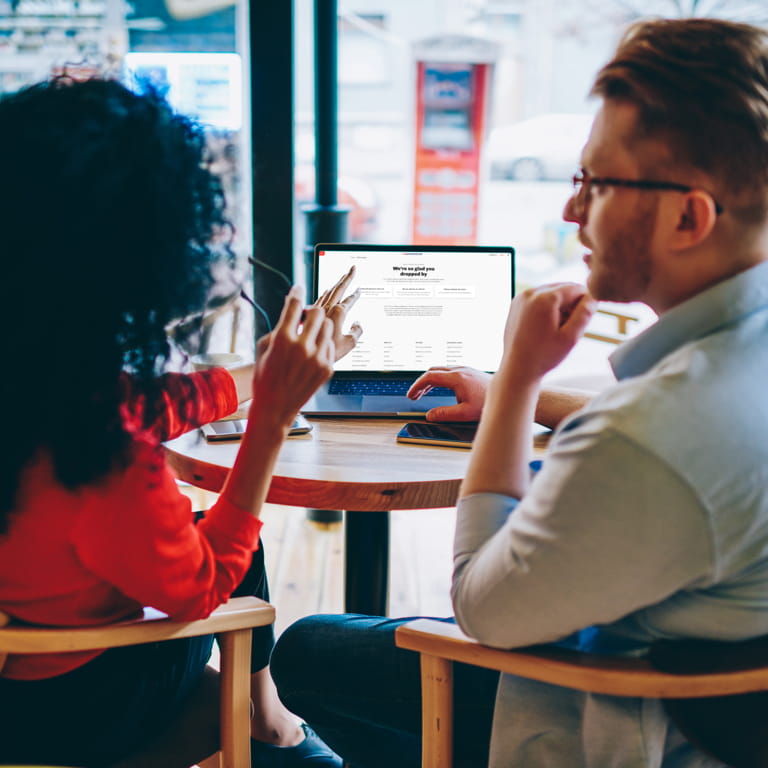             A financial advisor with her male client inside a coffee shop looking a laptop screen and discussing his future plans and finances. 