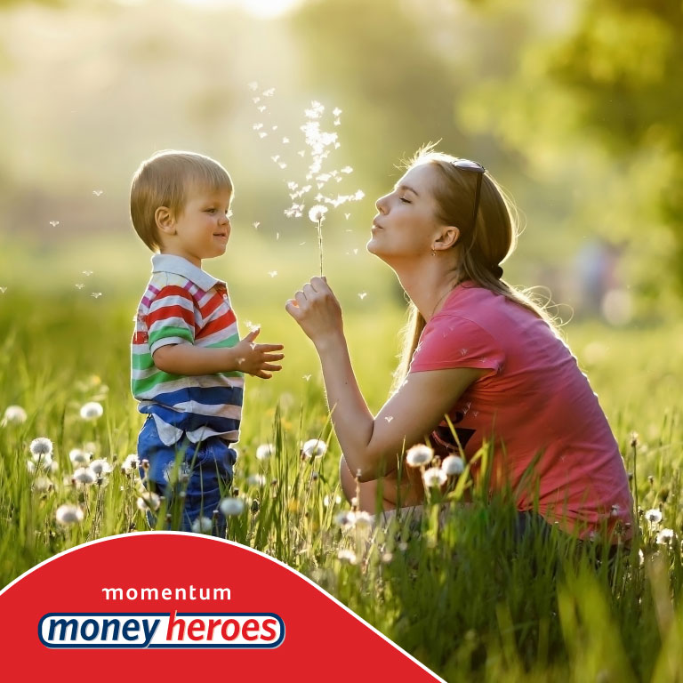 A mother and son in a green field blowing off the leaves of a dandelion. She recently updated her Will so that if she passed away, her son will be taken care of financially.