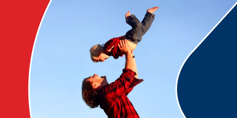 Young father throwing up his little son into air and catching him in his hands