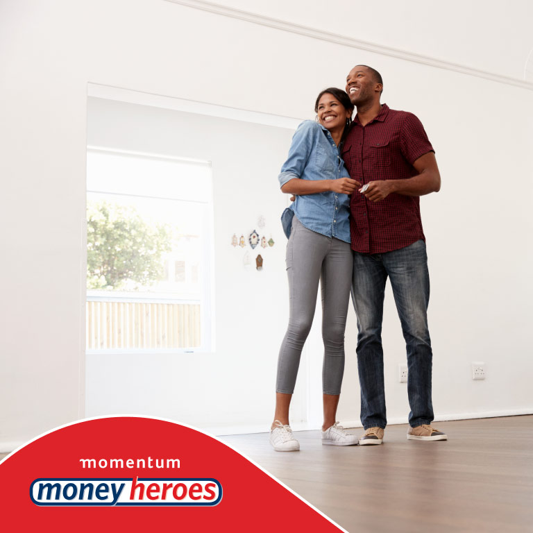 Young couple standing and looking very happy in their new home that they’ve just purchased.
