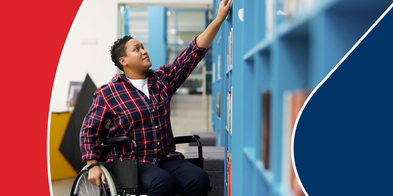 A person with a disability sitting in a wheelchair reaching up with their left arm to get a book from a shelf. They continue with life living off the income provided by disability insurance.