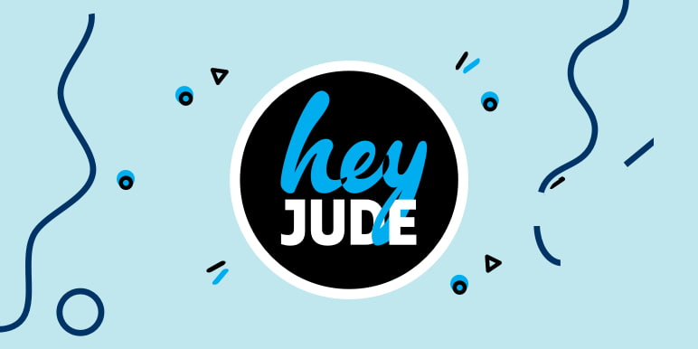 A young man with a flowery blue and white long-sleeved shirt, leaning against a wooden barrel accessing the Hey Jude app to assist him with tasks he cannot get to in his day.