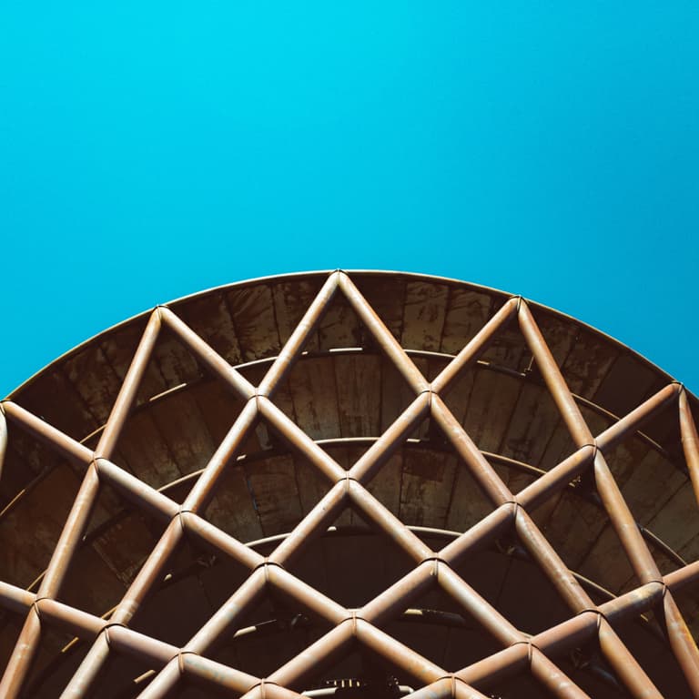 Diamond shaped steel structure with a blue sky background.