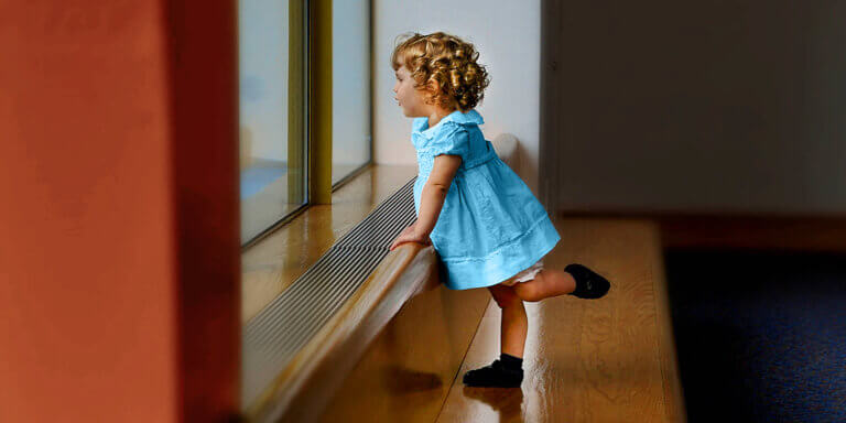 Toddler in blue dress looking out the window to symbolise looking ahead at the prospect of a bright financial future.  