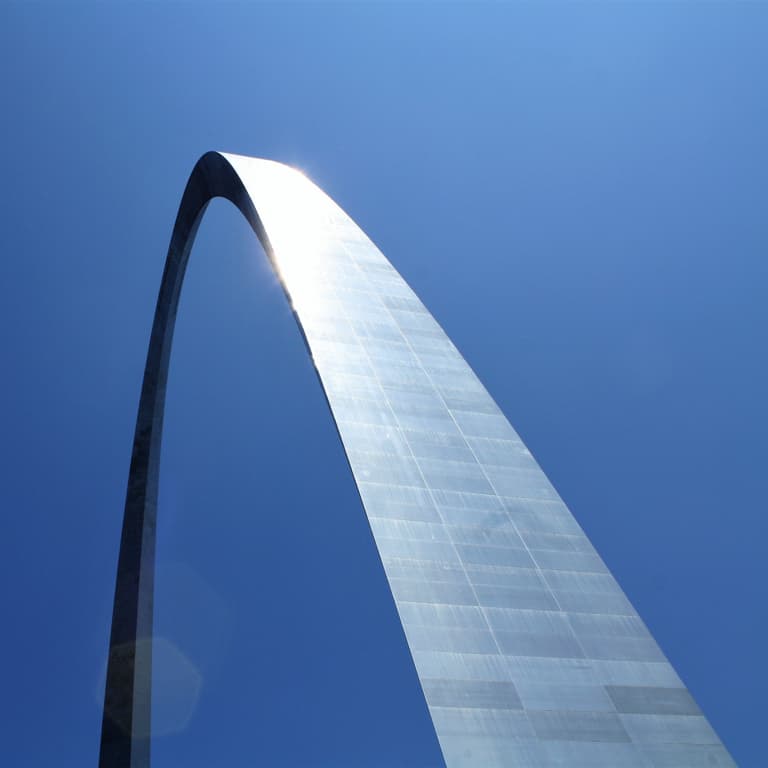 A high rising and arching silver steel structure with a blue sky background.