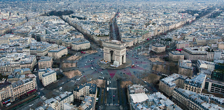 The Arc de Triomphe in Paris, France, surrounded by a big traffic circle, with all roads leading towards it.