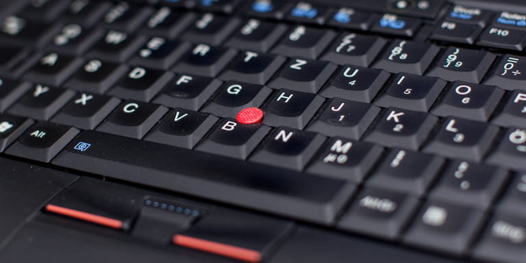 Black laptop keypad with white letters and a red trackpoint.