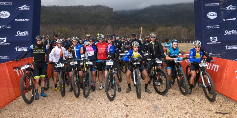 Two mountain bike cyclists in rugged terrain cycle past a vast mountainous area on the Merino Monster climb.