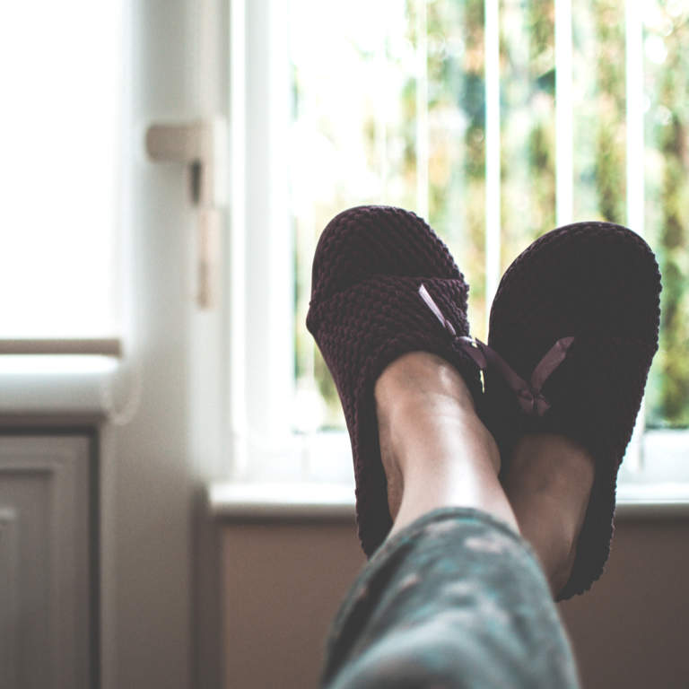 Young woman's legs in warm, soft, comfortable slippers at home resting her feet while she recovers from being ill.