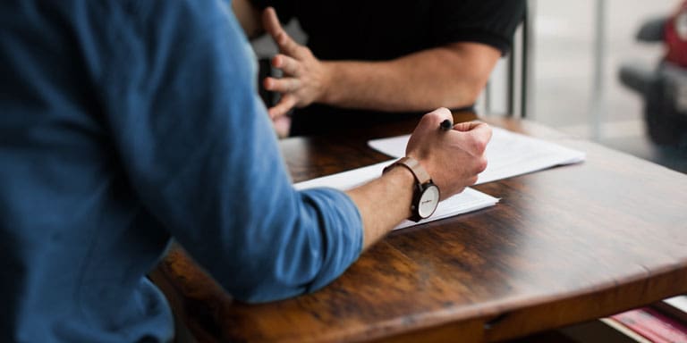 A financial advisor and a client sitting at a table, going through financial planning documents.