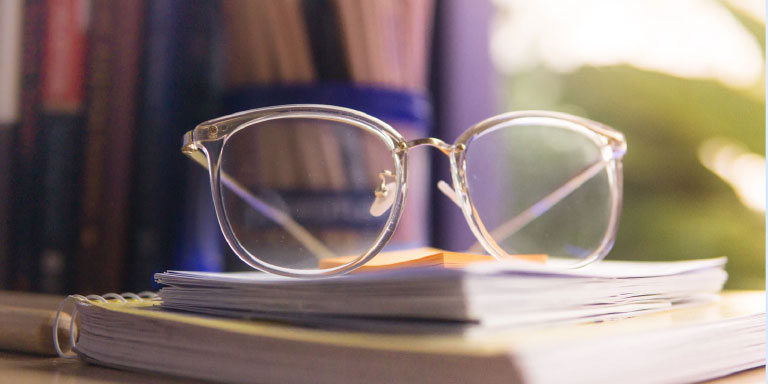 A pair of eye glasses placed onto a life insurance policy document on a desk.